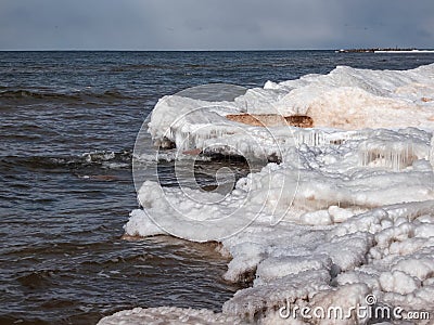 Landscape of Baltic sea and beach with ice and snow formations on the shore in bright sunlight. Frozen ice blocks and sea water in Stock Photo