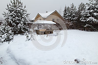 Landscape with barbeque area, snowbanks of white snow, pine trees in country garden. Stock Photo