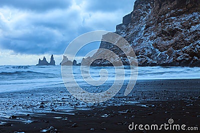 Landscape with the beach of black sand, dramatic sky and the sea stacks in the background at twilight in winter, Reynisdrangar ne Stock Photo