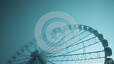 Blue-tinted image of a large ferris wheel on a cold morning Stock Photo