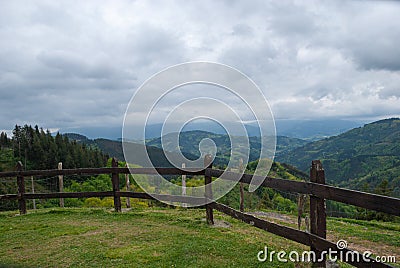 Landscape with green meadows and wooden fence with mountains Stock Photo