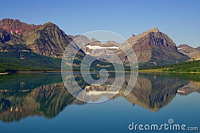 Landscape of a lake surrounded by rocky hills reflecting on the water under the sunlight Stock Photo