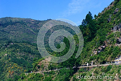 Landscape with mountains, forest and pines, cottages, mountain houses, blue sky, clouds, twisting road & terrace farms. Stock Photo