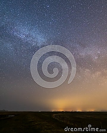 Landscape night shot with the milky way and a dyke and a moor in the forground Stock Photo