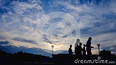 Silhouette scene a group of runner running on the lane at the stadium area against blue sky white fluffy clouds Stock Photo