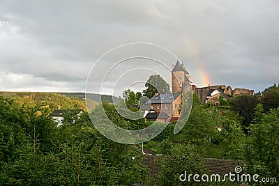 Landscape photo of Muerlenbach in the Eifel in summer with a rainbow and Bertrada Castle Stock Photo