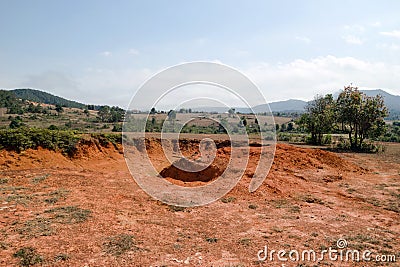 Landscape with red dry cracked soil between hills and mountains in Xieng Khouang Province, Laos Stock Photo