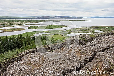 Landscape with rocks, Oxara river and large Thingvallavatn lake in Thingvellir, Iceland in overcast weather Stock Photo