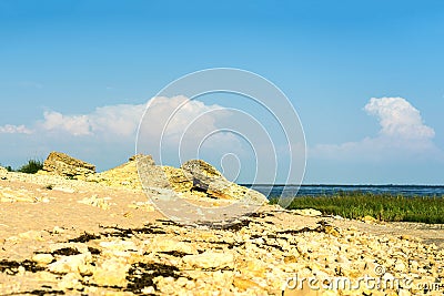 Landscape of a sandy beach with rocks, grass, sea, blue sky Stock Photo