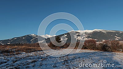 Landscape of snow covered agricultural field with some clumps of grass peeping out. Stock Photo