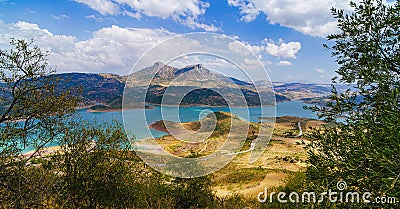 Landscape of turquoise lake with mountains and hills in andalusia with road meadows and bushes Stock Photo