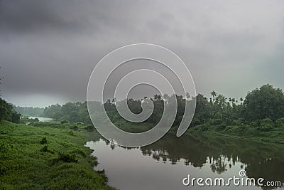 A landscape view of a calm river with green trees and mountain in India Stock Photo