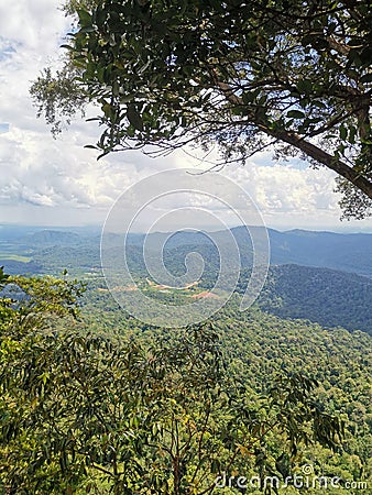 Landscape view of mountain range and cloudy blue sky with trees foreground, view from rainforest mountain peak of Gunung Panti Stock Photo