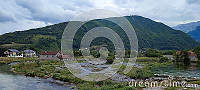 Landscape view over Lim river, with a swamp near houses, forested mountain and cloudy sky background Stock Photo