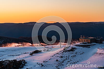 Landscape view with snowy and rocky mountain at sunset, fiery sky and sun background Stock Photo