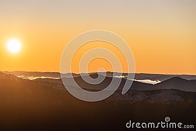 Landscape view with snowy and rocky mountain at sunset, fiery sky and sun background Stock Photo