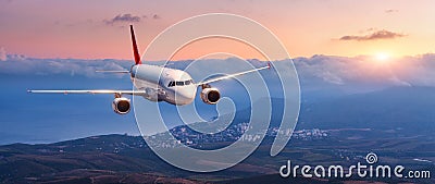 Landscape with white airplane is flying in the orange sky Stock Photo