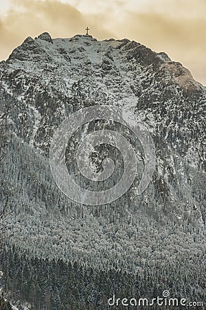 Landscape wtih Caraiman mountain wall with the cross of the heroes on the top of Caraiman in winter season - Bucegi Stock Photo