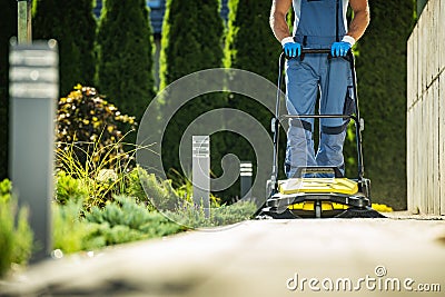 Landscaper Worker with Push Sweeper Cleaning Garden Pathway Stock Photo