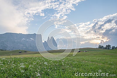 Landscapes on Alpe di Siusi with Schlern Mountain Group in Background and small cabins on the grassland in Summer during the sunse Stock Photo