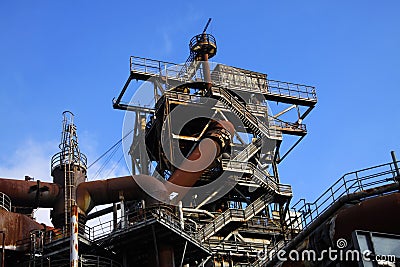 Landschaftspark Duisburg, Germany: Low angle view on stairways into deep blue sky at corroded tower with rusty pipeline Stock Photo