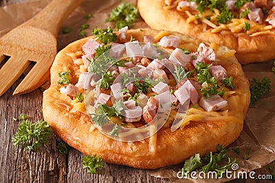 Langos deep fried with cheese and ham close-up. Horizontal Stock Photo