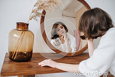 Languid woman in a white dress in front of the mirror Stock Photo