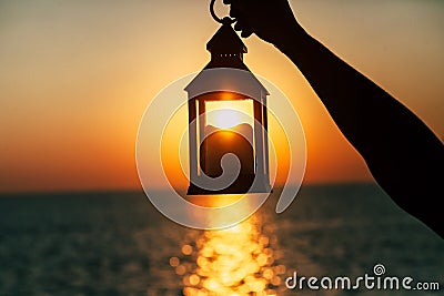 A lantern with a candle in the hand at dawn. Stock Photo