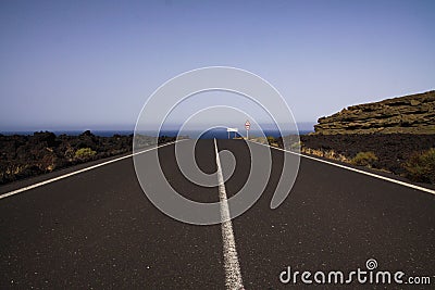 Lanzarote - Timanfaya NP: Driving trip on endless empty asphalt road between black lava rocks in barren landscape to atlantic Stock Photo
