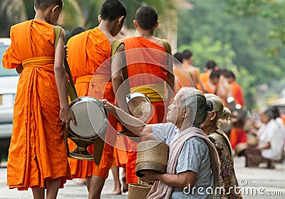 Laotian people making offerings to Buddhist monks during traditional alms giving ceremony in Luang Prabang city, Laos Editorial Stock Photo