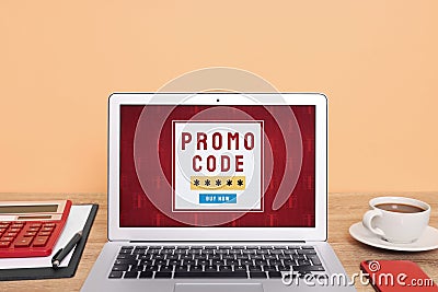 Laptop with activated promo code on wooden table near beige wall Stock Photo