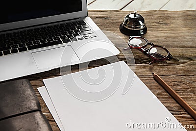 The laptop, blank paper, glasses and small bell on Stock Photo