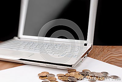 Laptop with blank screen and heap of coins on wooden table Stock Photo