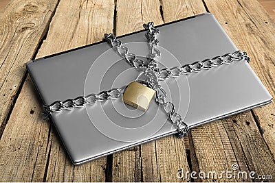 Laptop with chains and padlock on wooden Stock Photo