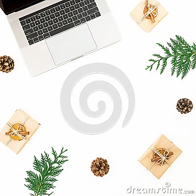 Laptop with Christmas gifts, evergreen branches and pine cones on white background. Holiday office composition. Top view. Flat lay Stock Photo
