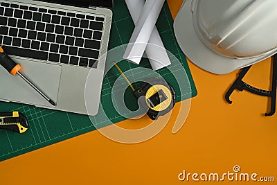 Laptop computer, blueprints, safety hardhat, coffee cup and stationery on yellow background Stock Photo