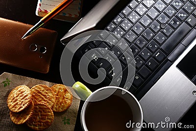 Laptop computer, cup of coffee, ballpen, notebook, crackers, and a smartphone Stock Photo