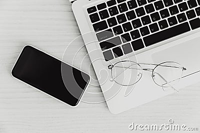 Laptop computer on the desk with smartphone and glasses top view monotone for minimal business flat lay picture Stock Photo