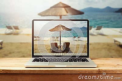 Laptop computer with sunny beach image on wooden table. Summer vacation photo Stock Photo