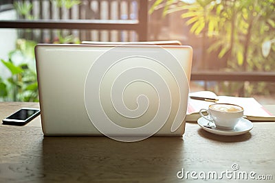 Laptop and cup of coffee and cell phone with books and pen on wooden table Stock Photo