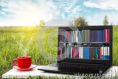 Laptop and cup of hot coffee on the background picturesque nature, outdoor office. E-book library concept. Internet books store. Stock Photo