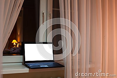 Laptop with cutout screen of monitor laying on windowsill at evening time in room Stock Photo