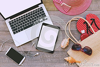 Laptop, digital tablet and smart phone with beach items over wooden background. View from above Stock Photo