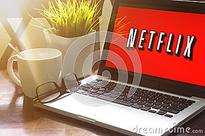 Laptop displaying Netflix word on wooden table Editorial Stock Photo