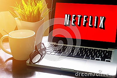 Laptop displaying Netflix word on wooden table Editorial Stock Photo
