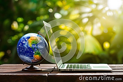 Laptop with earth globe on wooden table and green bokeh background Stock Photo