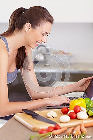 Laptop, food and a woman reading a recipe in her kitchen with vegetarian ingredients for health. Computer, smile and a Stock Photo