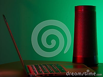 Laptop and Modern speaker with voice assistant on the table. Stock Photo