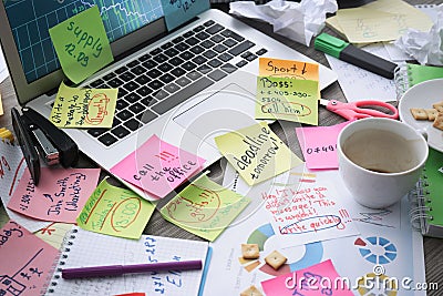 Laptop, notes and office stationery in mess on desk. Overwhelmed with work Stock Photo