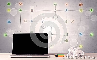 Laptop on office desk with media icons Stock Photo